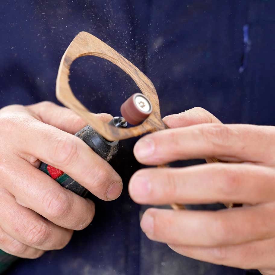 Lavorazione artigianale di una montatura in legno per occhiali con utensile di precisione.