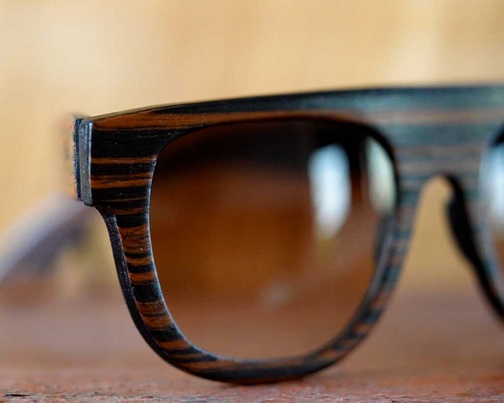 Dettaglio ravvicinato di una montatura in legno con venature naturali e lenti sfumate.